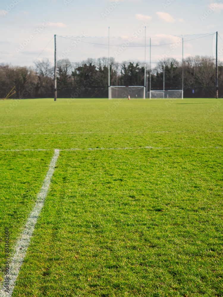 Markings on a training field in focus, Two goalposts for Irish National sport out of focus, Vertical image.
