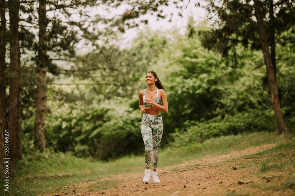 Young fitness woman running at forest trail