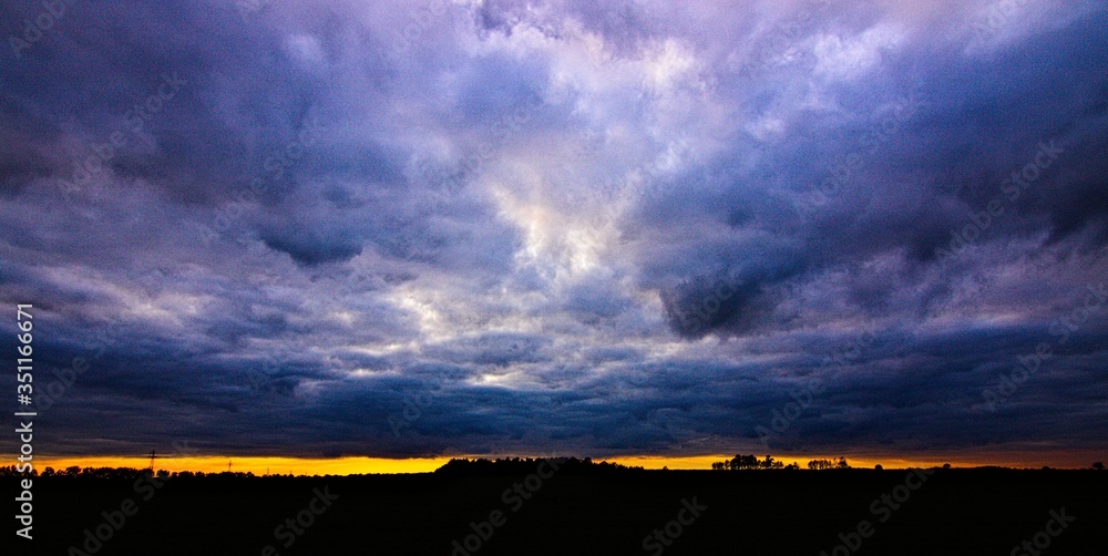 Stalowe chmury o zachodzie słońca - obrazy, fototapety, plakaty 