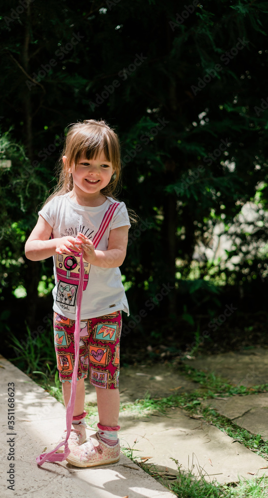 Beautiful little girl playing with a ribbon in the garden Beautiful little girl playing with a ribbon in the garden