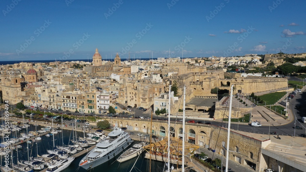 Aerial view of sailboats moored in harbour Senglea and Birgu, Bormla / Cospicua, Valletta, Malta. Ancient architecture of old town: christian orthodox churches, cathedrals, basilicas. Sunny day, blue 