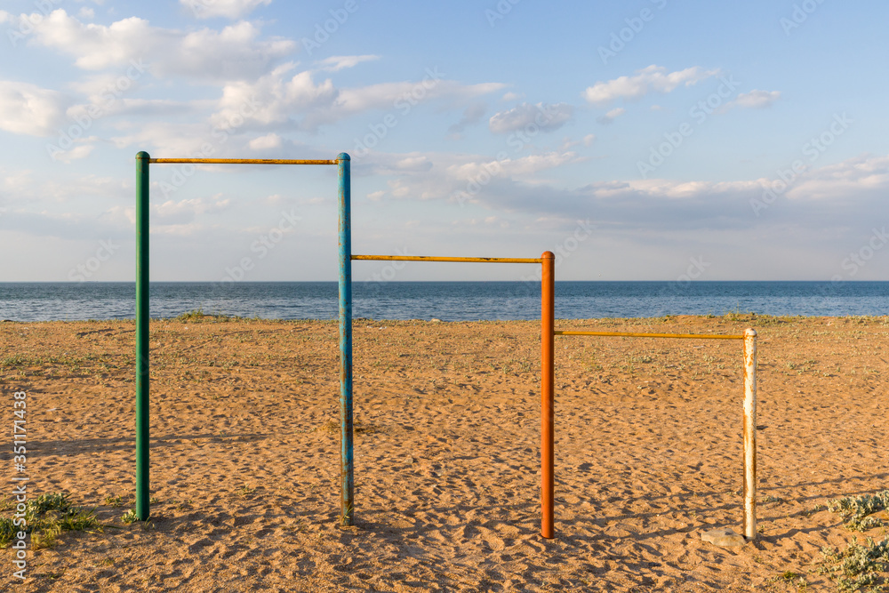 Large multi-colored turnstiles stand on the beach with clean blue sky. Large multi-colored turnstiles stand on the beach with clean blue sky.