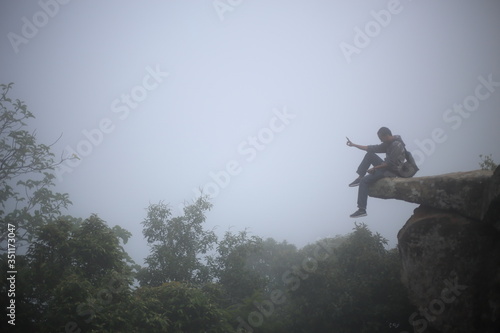Man sitting at the edge of a cliff Pa Hin Ngam National Park in Chaiyaphum, Thailand.