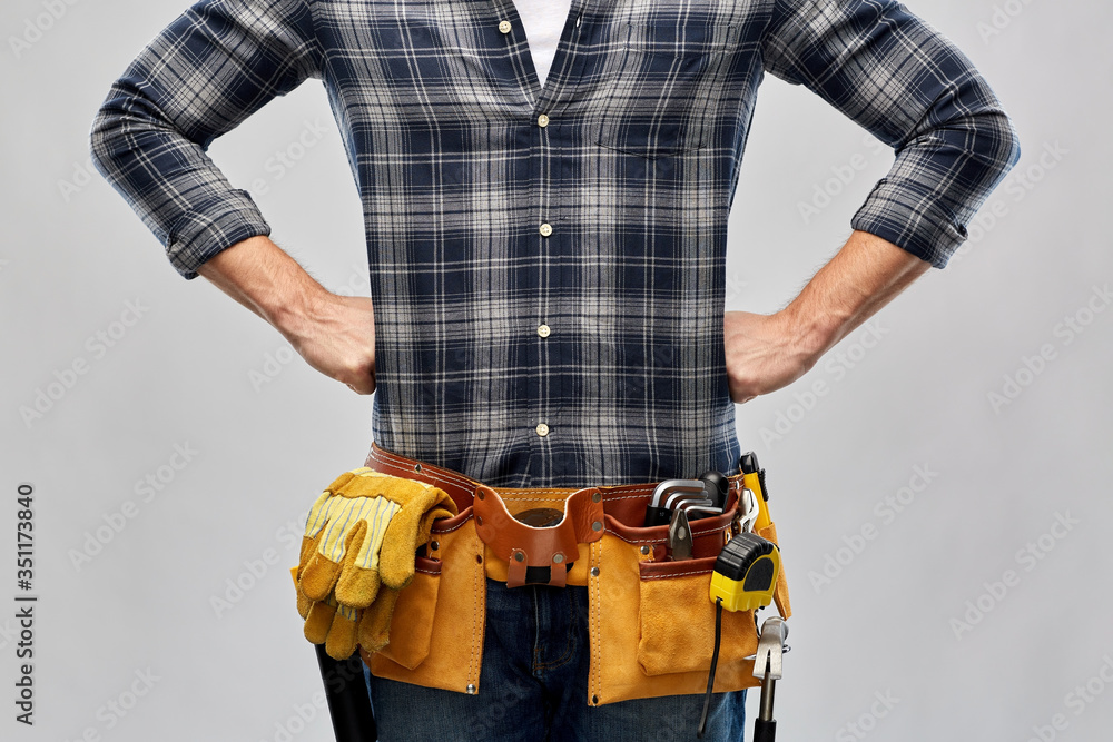 repair, construction and building - male worker or builder with working tools on belt over grey background repair, construction and building - male worker or builder with working tools on belt over grey background