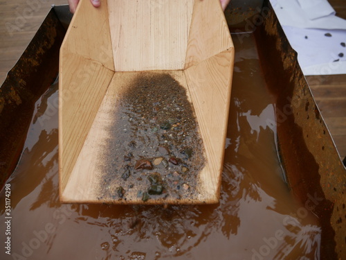 Search for gold nuggets in the gold-bearing rock in the old way using a wooden tray. photo