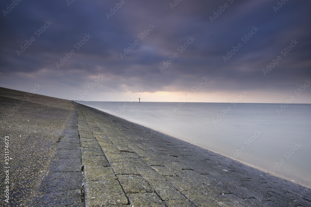 Impressive view from the dike at Moddergat, the Netherlands. Beautiful composition of stones, water and air. Sunset over the Wadden Sea. Unesco world heritage