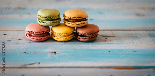 Close up of coloured and tasty hand made macarones cakes - sugar biscuits on a blue wooden trendy table - chocolatee and food energy concept photo