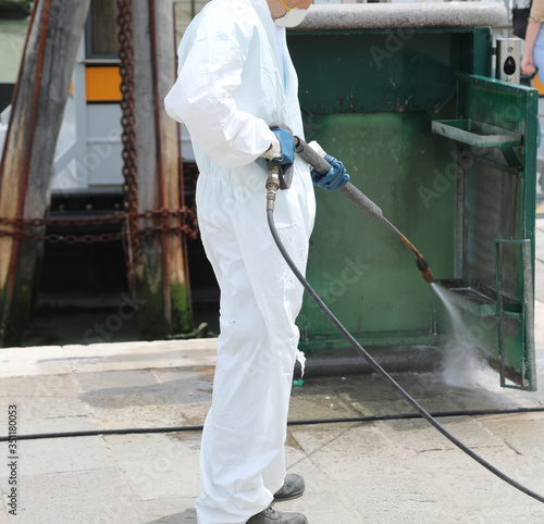 Worker during the disinfection with the jet of the pressure wash