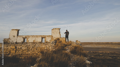 Hombre haciendo fotografía a restos arquitectónicos en las Saladas de Sástago Bujaraloz en el desierto de Monegros en Huesca al atardecer photo