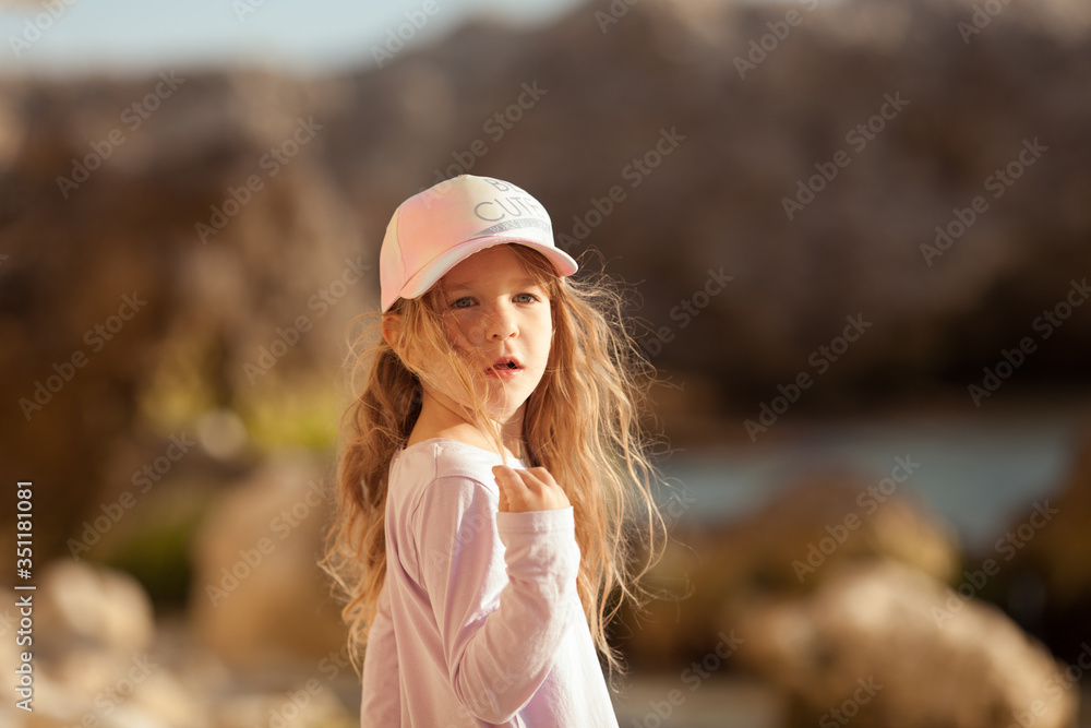 Obraz premium Happy pretty girl walks along the sea coast against the background of the sea, from behind a beautiful landscape