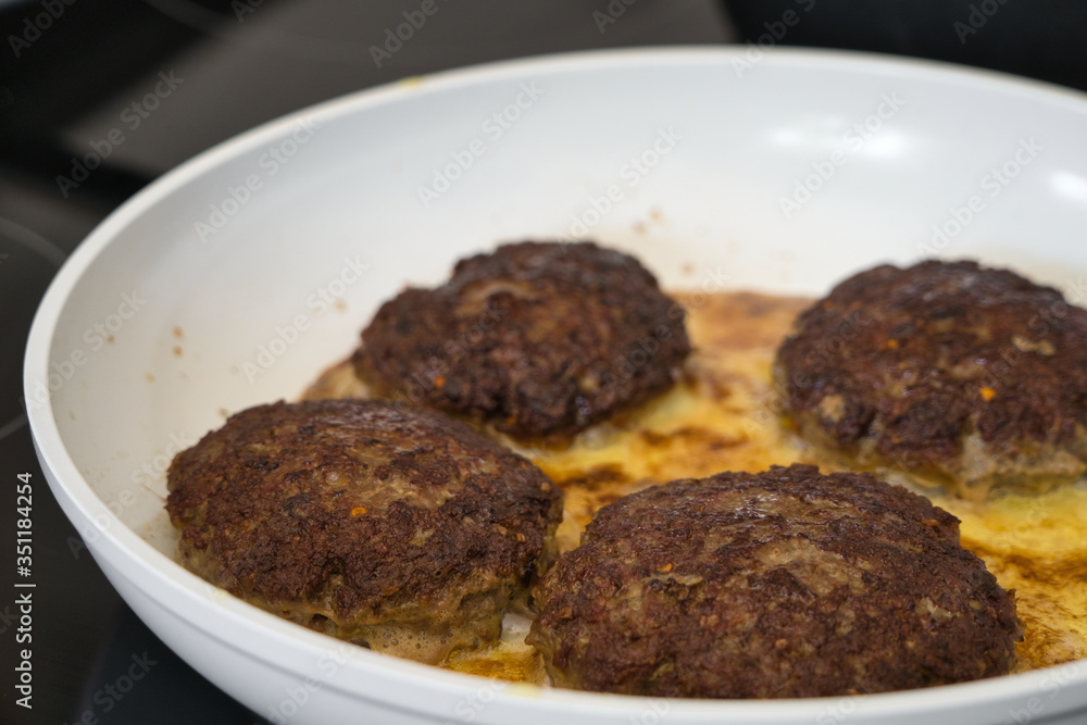 Frikadellen Gemüse Fleisch Paddys mit Kurkuma beim Anbraten in weißer Teflonpfanne mit Kokosöl, Produktbild Frikadellen Gemüse Fleisch Paddys mit Kurkuma beim Anbraten in weißer Teflonpfanne mit Kokosöl, Produktbild