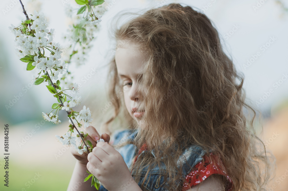 Cute little girl with curly hair in a flowering garden Cute little girl with curly hair in a flowering garden