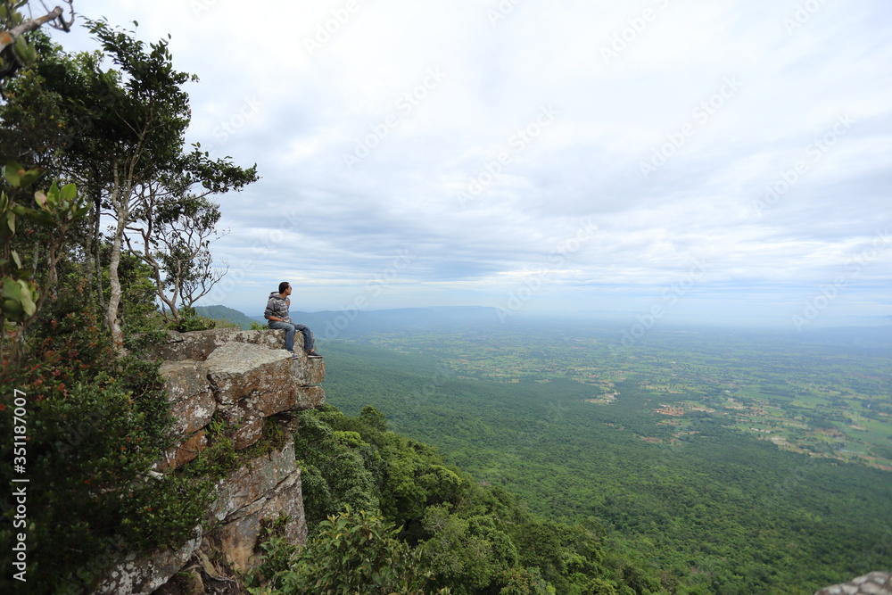 Man sitting on a cliff at Mor Hin Khao National Park in Chaiyaphum, Thailand