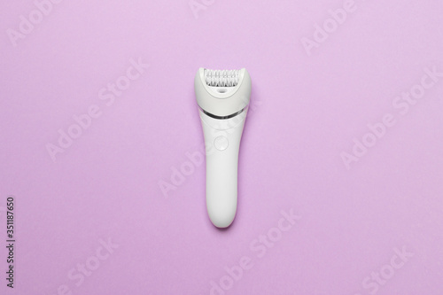 women epilator on purple colored paper background, top view