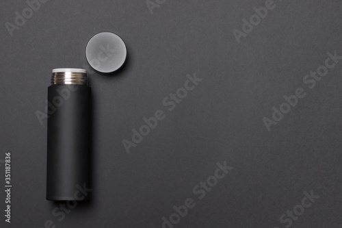 black thermos cup with open cover on black background with copy space