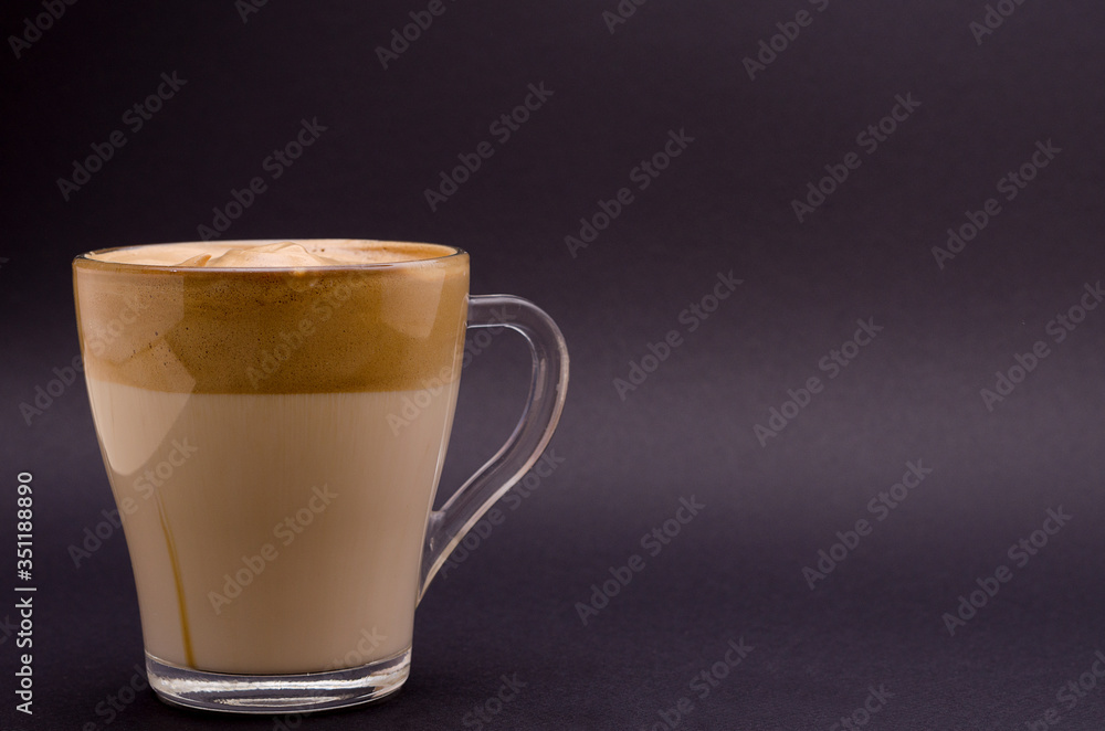 Dalgon iced coffee in a transparent glass on a dark background. Korean and Indian whipped coffee, copy space, horizontal image Dalgon iced coffee in a transparent glass on a dark background. Korean and Indian whipped coffee, copy space, horizontal image