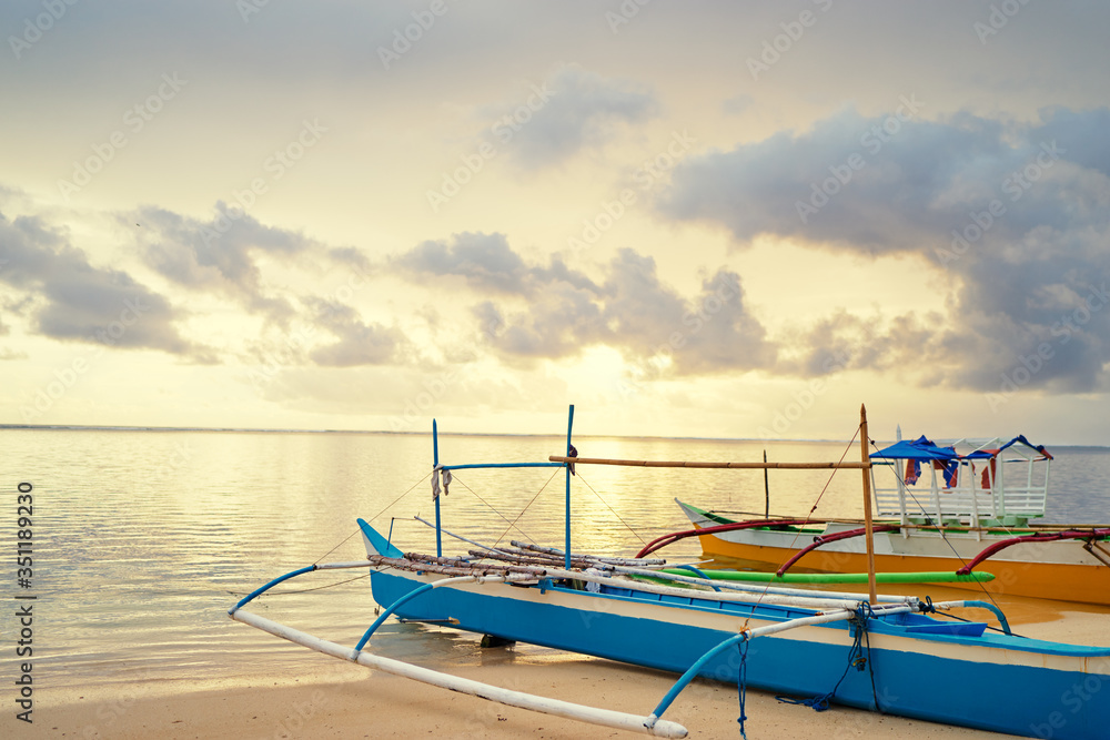 Beautiful colorful sunrise on the seashore with fishing boats. Philippines, Siargao Island.