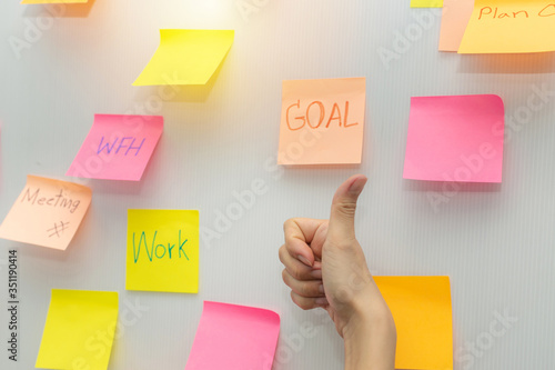 Goal. business woman showing thumbs up with colored sheets sticky note paper on white board background in office, business meeting, brainstorming, creative, digital online marketing, financial concept