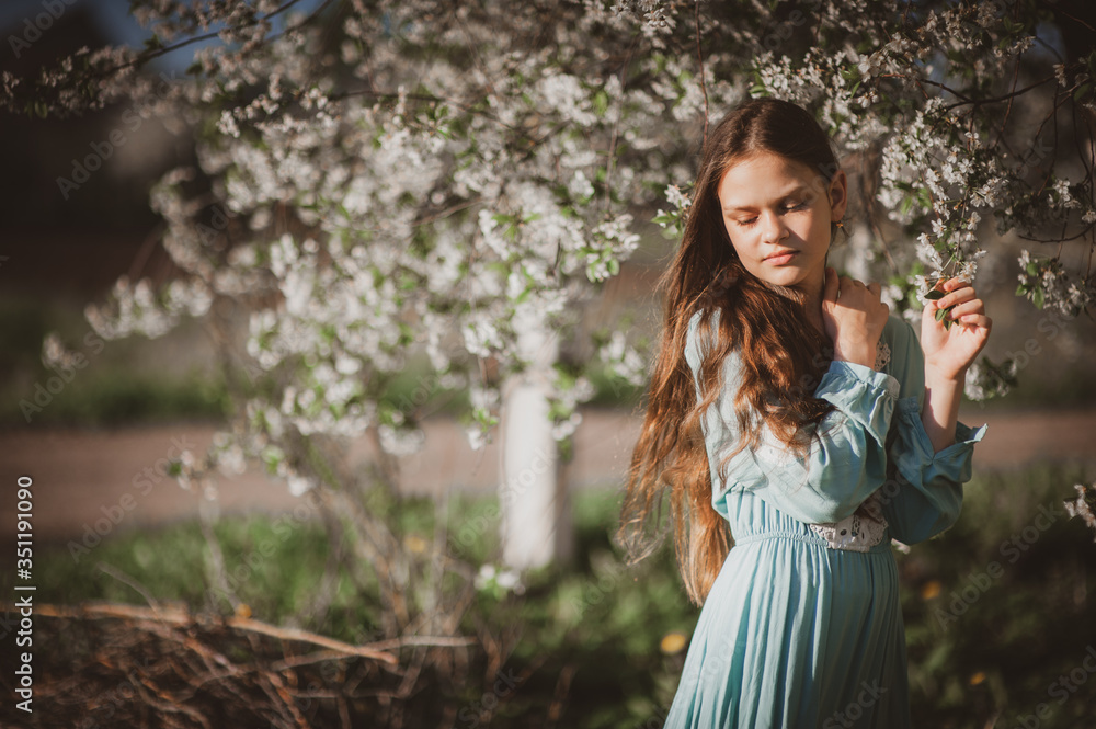 beautiful young girl with long flowing hair in a blooming cherry blossoms garden