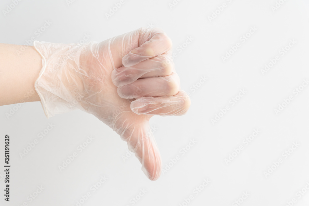 gesture thumb down, made by hand in medical glove on white background, communication skills, sign that means dislike.