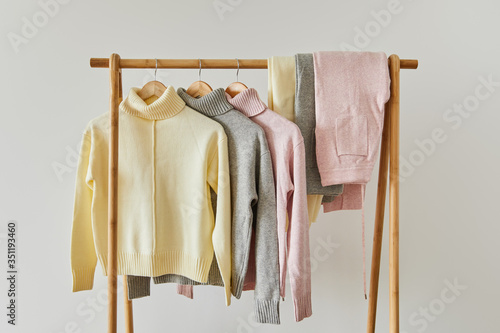 Wallpaper Mural pink, beige and grey knitted soft sweaters and pants hanging on wooden rack isolated on white Torontodigital.ca