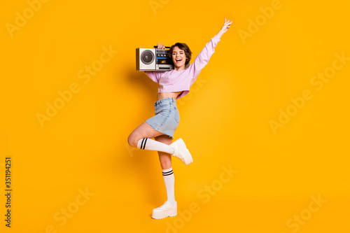 Full length body size view of her she nice attractive lovely cheerful funny girl carrying boombox having fun dancing retro vintage trend isolated on bright vivid shine vibrant yellow color background