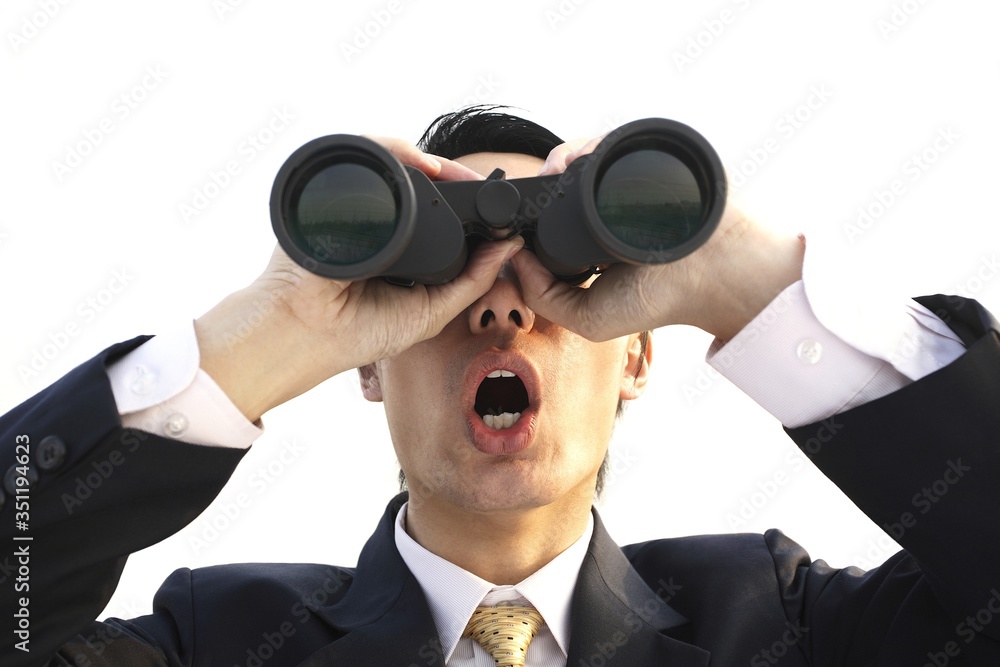 Businessman in shock while looking through a binoculars Businessman in shock while looking through a binoculars
