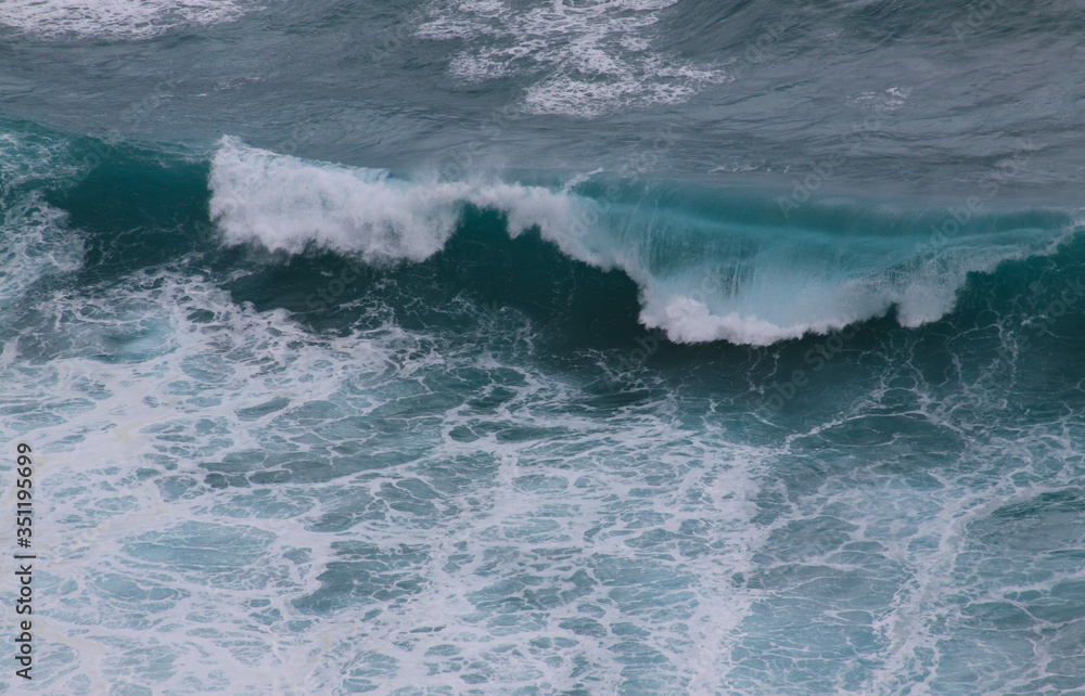 Fototapeta premium Blue and white breaking ocean wave seen from above