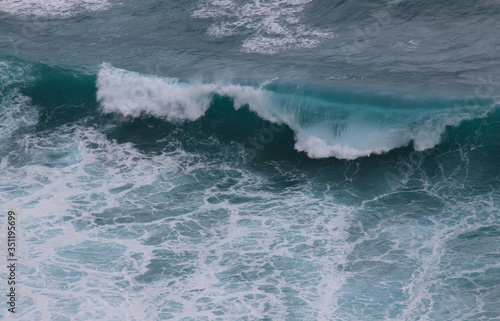 Blue and white breaking ocean wave seen from above