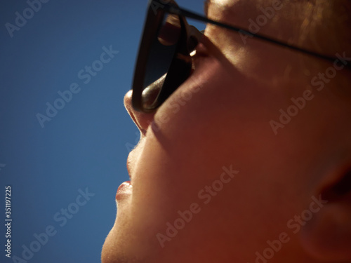 Face portrait of a girl in sunglasses on the sky