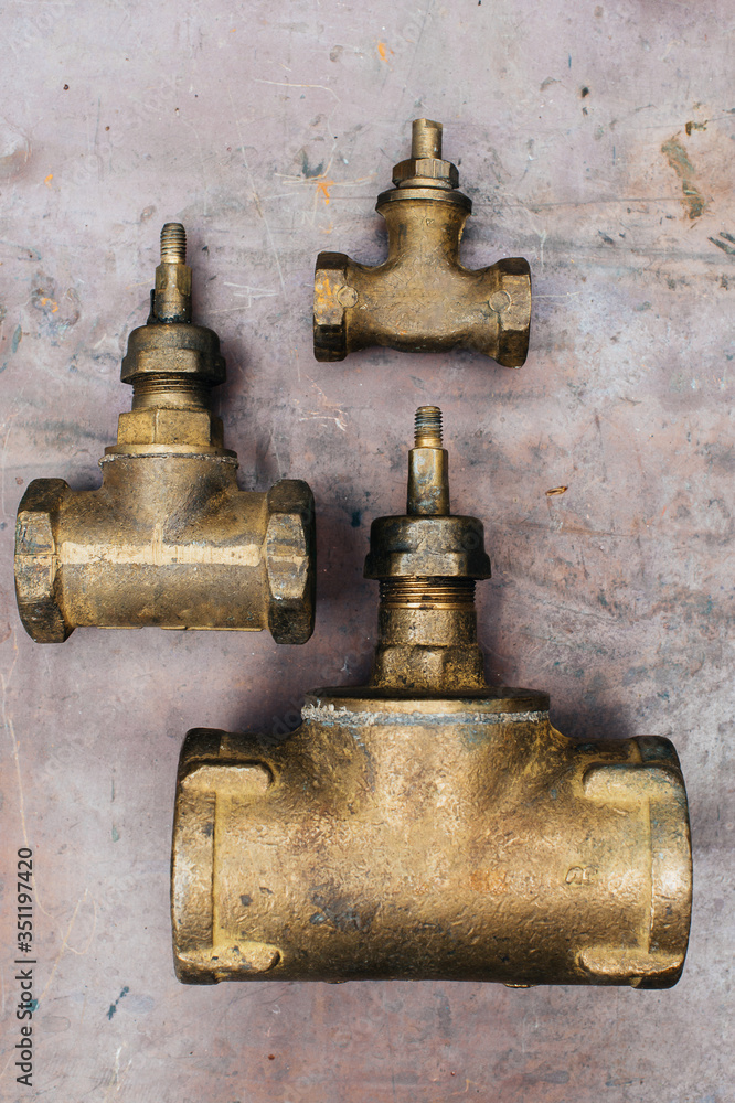 Brass scrap metal: taps, tees, plugs and various plumbing parts, spare parts. Against the background of a copper sheet. Close-up.