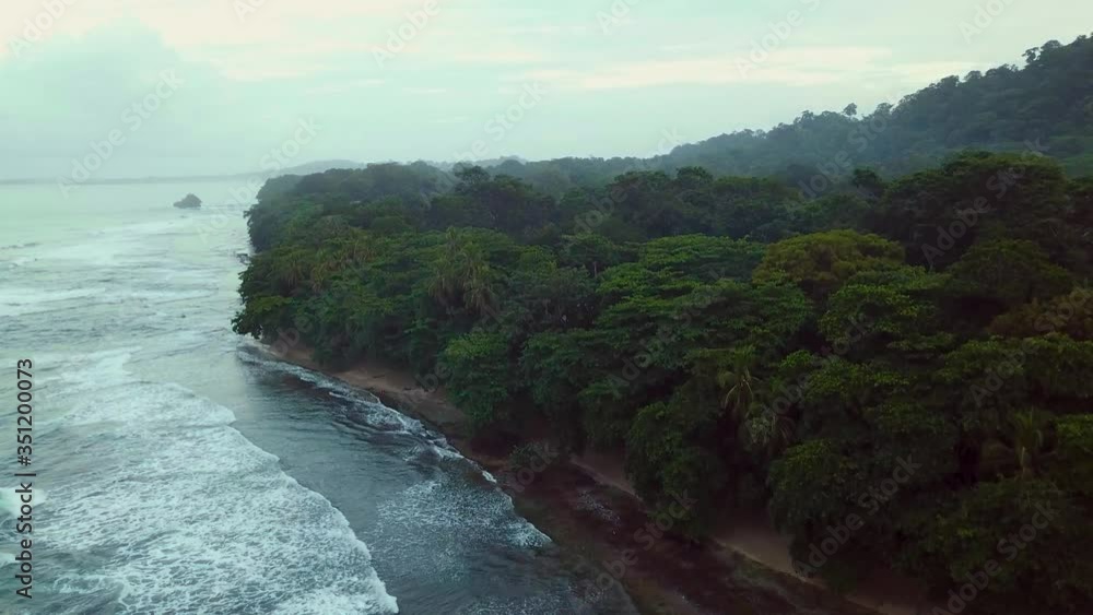 Aerial shot flying above a tumultuous Caribbean sea discovering the forest and ocean at dusk in Puerto Viejo de Talamanca in Costa Rica. Aerial shot flying above a tumultuous Caribbean sea discovering the forest and ocean at dusk in Puerto Viejo de Talamanca in Costa Rica.