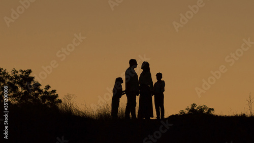 Silhouette of a happy family of four, mother, father, daughter, son at sunset