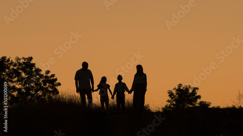 Silhouette of a happy family of four  mother  father  daughter  son at sunset