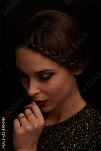 A portrait of a beautiful and shy woman in the dark. Lighting in Rembrandt style.