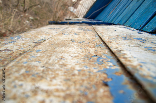 Old grunge painted boards with blue peeling paint on a wooden surface closeup selective focus background.
