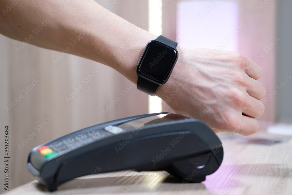 Fototapeta premium man using terminal for contactless payment with smart watch at table, closeup.
