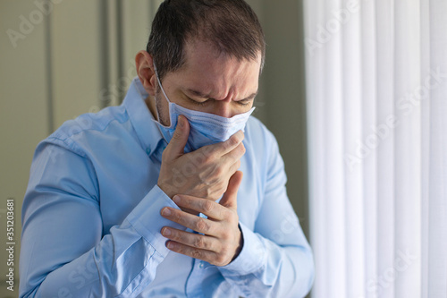 Young man coughing in a medical mask