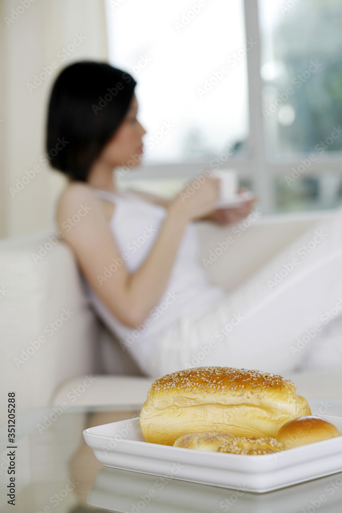 Woman enjoying tea with a tray of bread