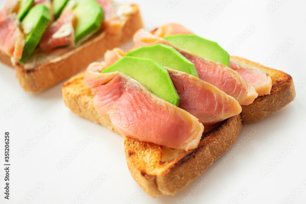 Avocado and salmon sandwich on toasted bread close up