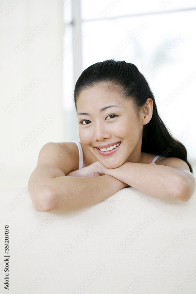Woman sitting on couch smiling at the camera Woman sitting on couch smiling at the camera