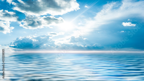 Sea landscape, sea surface. Blue sky, clouds, sunlight, rays. Empty natural scene in the open air. Blurred abstract background. Background of a sea landscape. Blue sky with clouds over the sea.  © MiaStendal