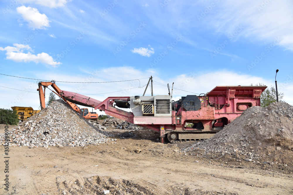 Mobile Stone Jaw crusher machine for crushing concrete into gravel and subsequent cement production. Salvaging and recycling of the demolition construction waste on landfill. Reuse concrete.