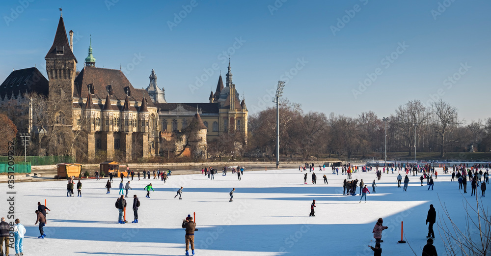 Fototapeta premium Panoramic view of people on ice skating rink near the Vajdahunyad Castle. Budapest, Hungary.