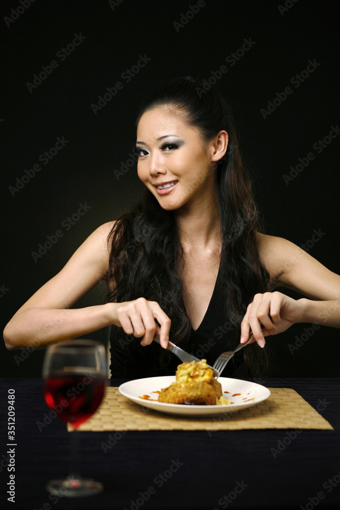 Woman smiling at the camera while enjoying her meal