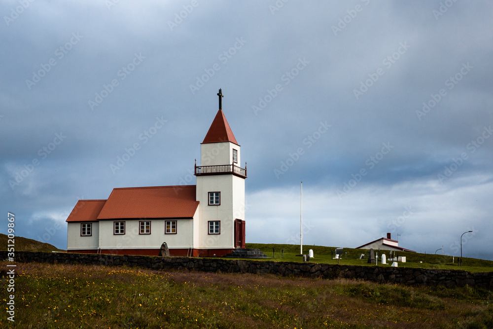 
Landscape on Grimsey Island in northern Iceland beyond the Arctic Circle. A white church with a red roof is visible, surrounded by a cemetery with white tombs