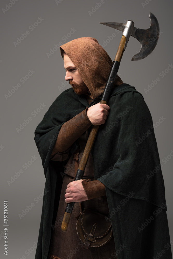 medieval Scottish redhead man in mantel with battle axe on grey background medieval Scottish redhead man in mantel with battle axe on grey background