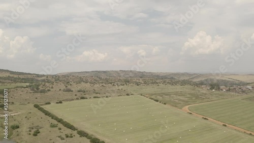 Drone shots of a South African farm and its vast fields of grass and crops, bales of hay and mountains in the background on a cloudy day photo