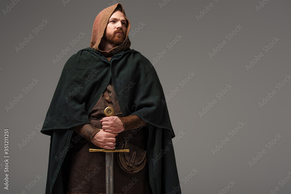 medieval Scottish redhead knight in mantel with sword on grey background  foto de Stock | Adobe Stock