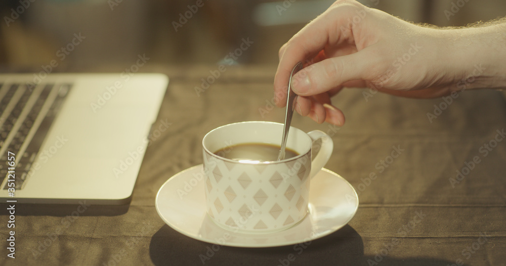 Man stirs his black coffee in the morning using a silver spoon Man stirs his black coffee in the morning using a silver spoon